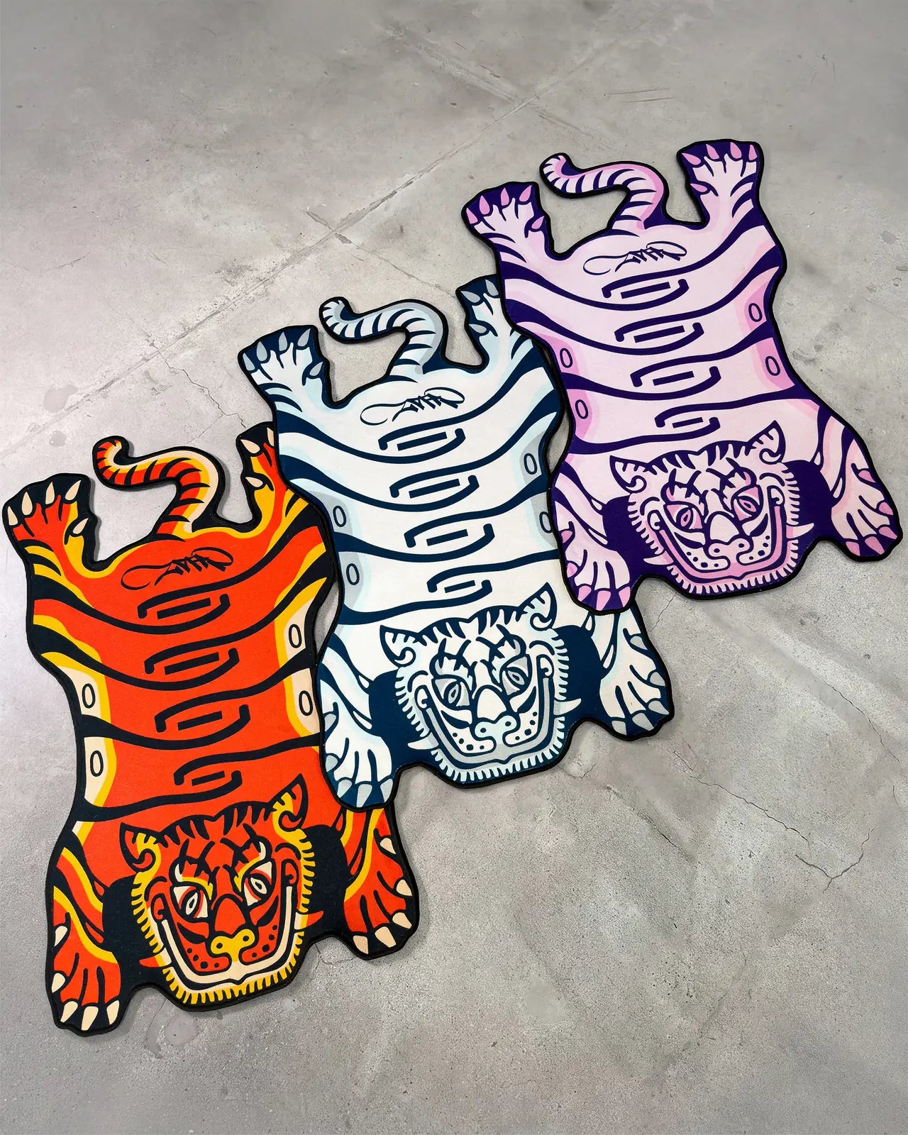 Orange, blue and purple Tuned Tiger rugs on concrete